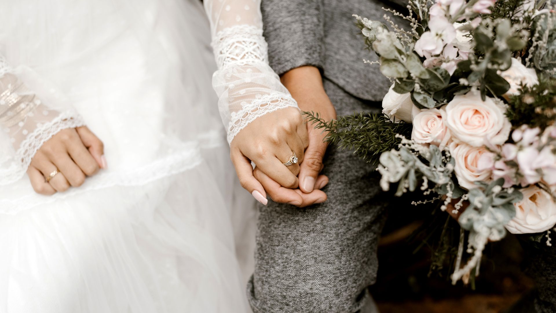 A photo of a newly wed couple holding hands and a bouquet of flowers.
