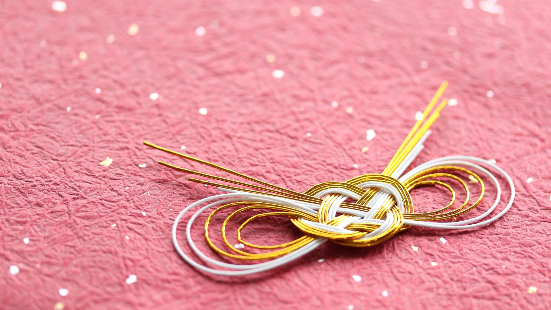 Photo of beautifully packed gift, wrapped in pink paper, with golden ribbon.