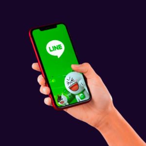 Image of a hand holding a mobile phone with LINE characters on the screen.